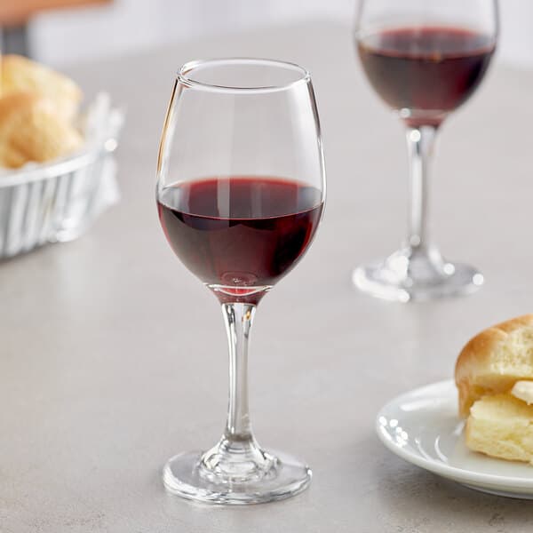 An Acopa all-purpose wine glass filled with red wine next to a plate of bread.