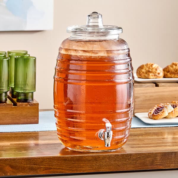 An Acopa glass beverage dispenser filled with a drink on a table.
