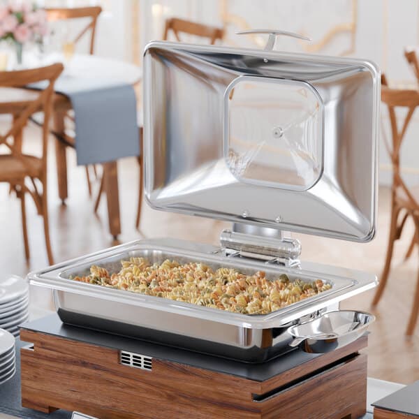 An Acopa Voyage stainless steel chafer with food on top on a table with a blue tablecloth.