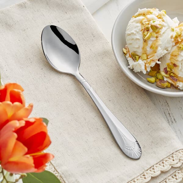 A bowl of ice cream with nuts and a spoon on a table.