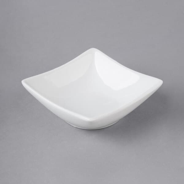 An Acopa bright white square porcelain sauce cup on a gray surface.