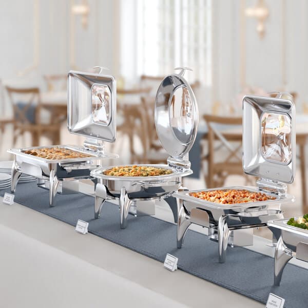 An Acopa Voyage chafer with a glass top on a buffet table with several different types of food.