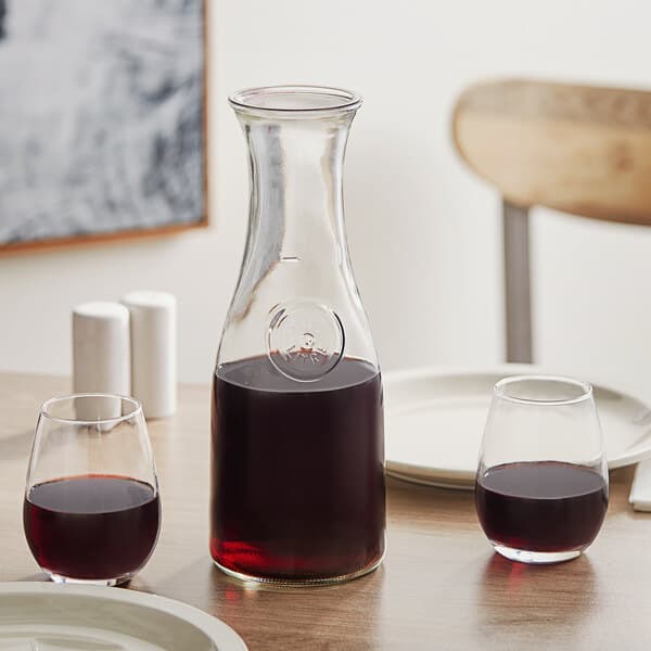 An Acopa glass carafe filled with red wine on a table.
