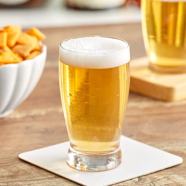An Acopa Barbary beer tasting glass with beer on a table.
