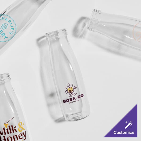 A group of Acopa glass milk bottles with a logo on them.