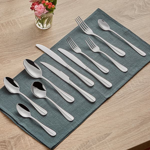 An Acopa Benson stainless steel serving spoon on a blue napkin.