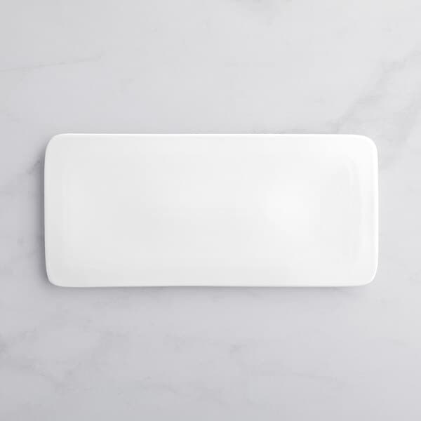 An Acopa bright white rectangular porcelain plate on a white marble surface.