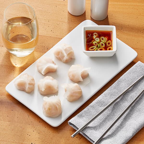 A rectangular white Acopa porcelain plate with food and chopsticks on a table.