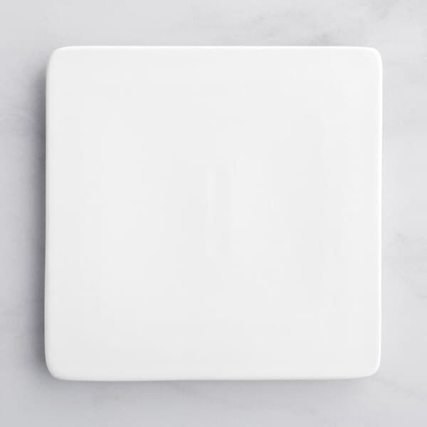 An Acopa bright white square porcelain plate on a marble surface.