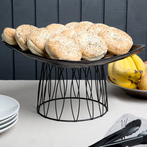 An Acopa black metal display stand with bagels on a table.