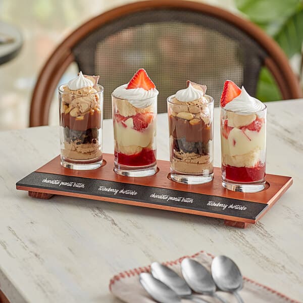 An Acopa flight tray with Straight Up Tasting Glasses filled with desserts on a table.