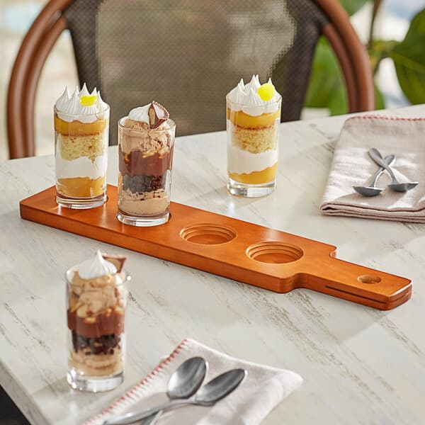 An Acopa flight paddle with desserts in glasses and spoons on a table.