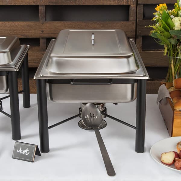 A buffet table with two Acopa wrought iron chafers on a white surface.