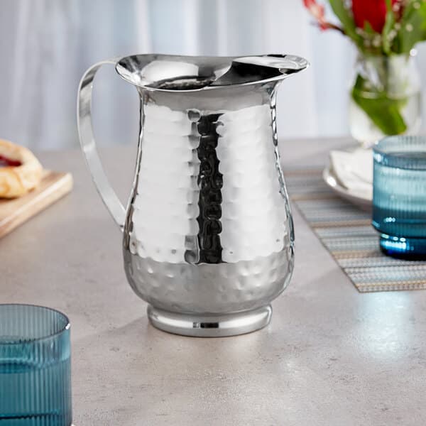 An Acopa stainless steel pitcher on a table.