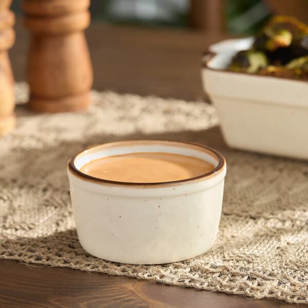A small vanilla bean stoneware ramekin filled with sauce.