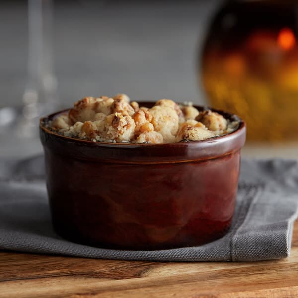 A bowl of food in an Acopa Chestnut stoneware ramekin on a table with a napkin.
