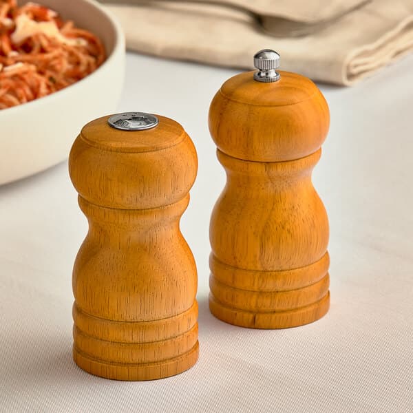 A brown wooden salt shaker and pepper mill set on a table.