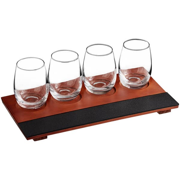 An Acopa wood flight tray with four stemless wine tasting glasses.