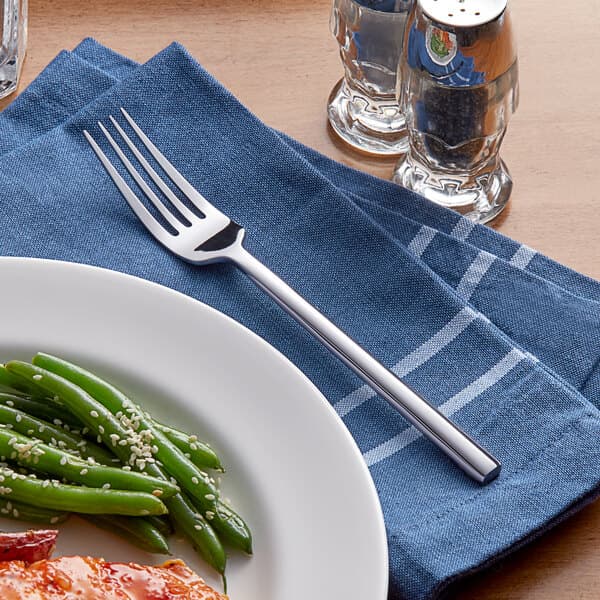 A fork on a plate of food with green beans.