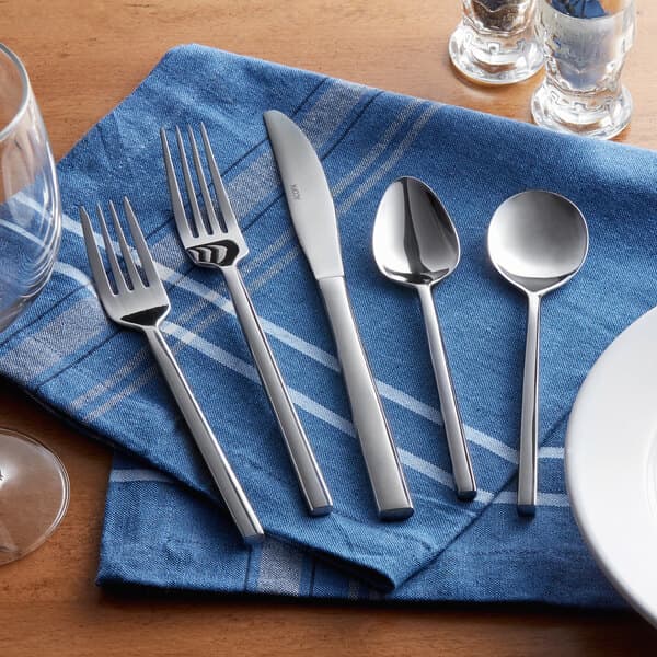 A close-up of an Acopa Phoenix stainless steel salad/dessert fork on a blue napkin.