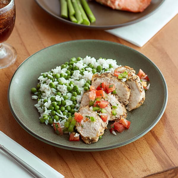 A close-up of an Acopa Moss Green Matte stoneware plate with rice, peas, and meat.
