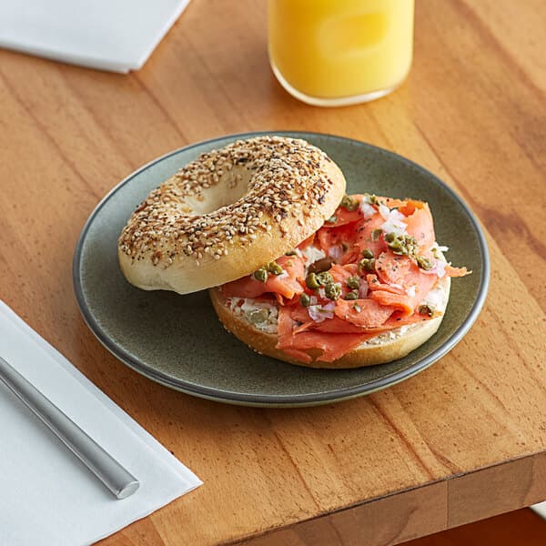An Acopa Embers moss green stoneware plate with a bagel sandwich on it.