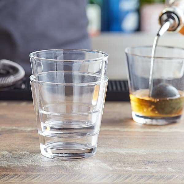 A person pouring a drink into an Acopa Select stackable rocks glass.