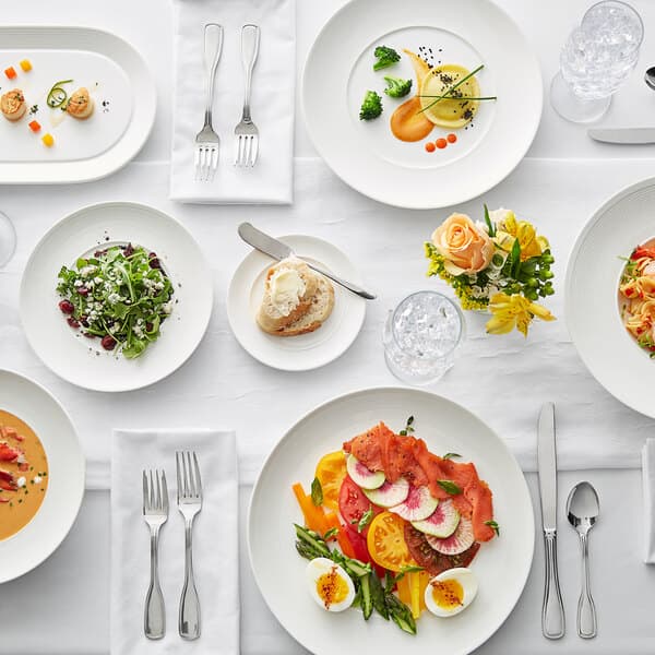 A table set with Acopa Liana porcelain plates filled with food and silverware.