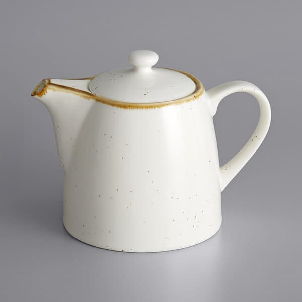 A white teapot with a brown speckled design and a handle.