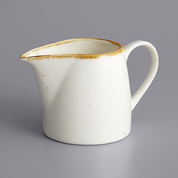 A white stoneware creamer with a white handle and brown accents.