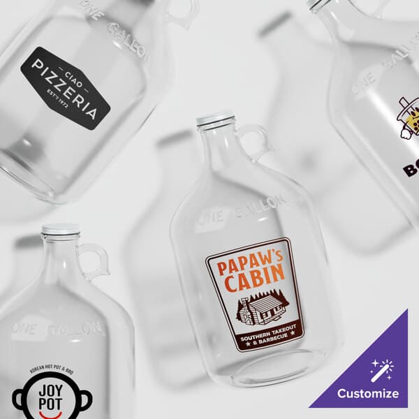 A group of clear glass Acopa growlers with black caps.