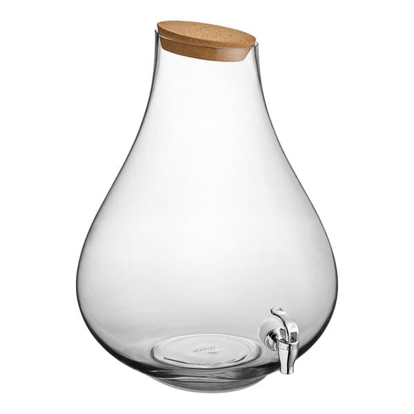 An Acopa clear glass beverage dispenser with a cork lid and metal spigot.