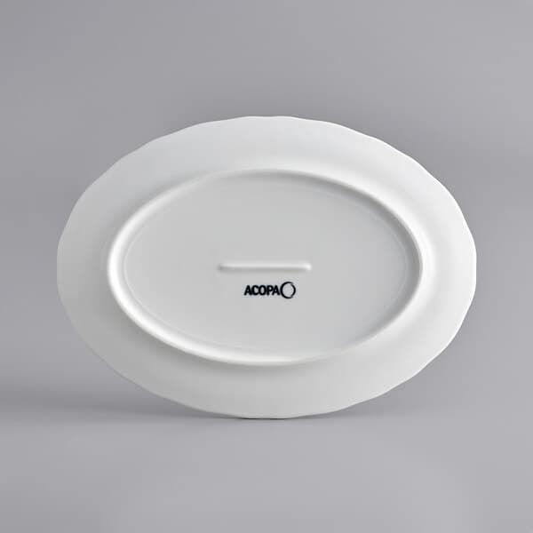 A white Acopa porcelain platter with a scalloped edge and a white oval with black text.