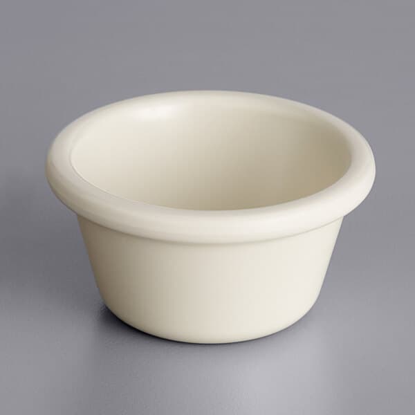 An Acopa bone white melamine ramekin on a gray surface.