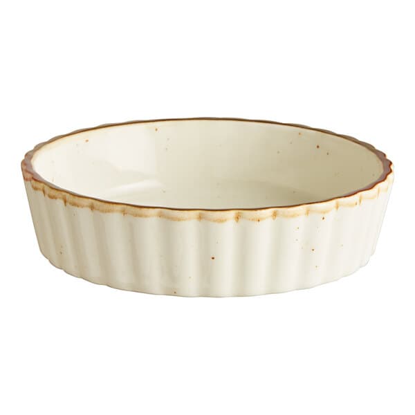 A round, fluted, cream-colored stoneware souffle or creme brulee dish with a slightly rustic finish.