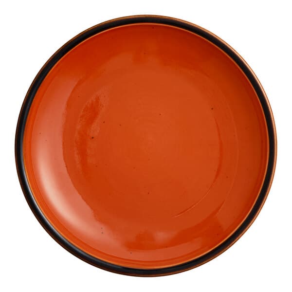 A small orange stoneware coupe plate with a dark rim.