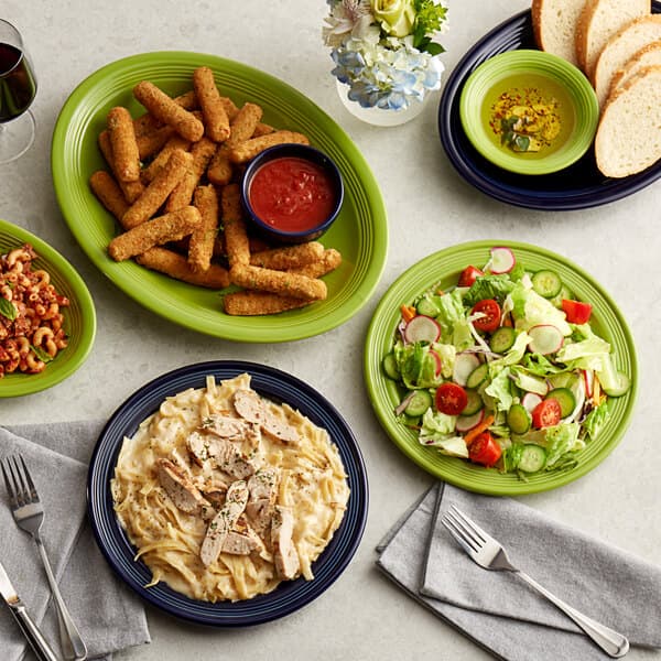 A table with Acopa Capri stoneware plates of food including salad.
