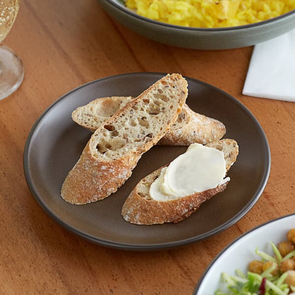 A piece of bread and a plate of food on an Acopa Embers coupe plate.