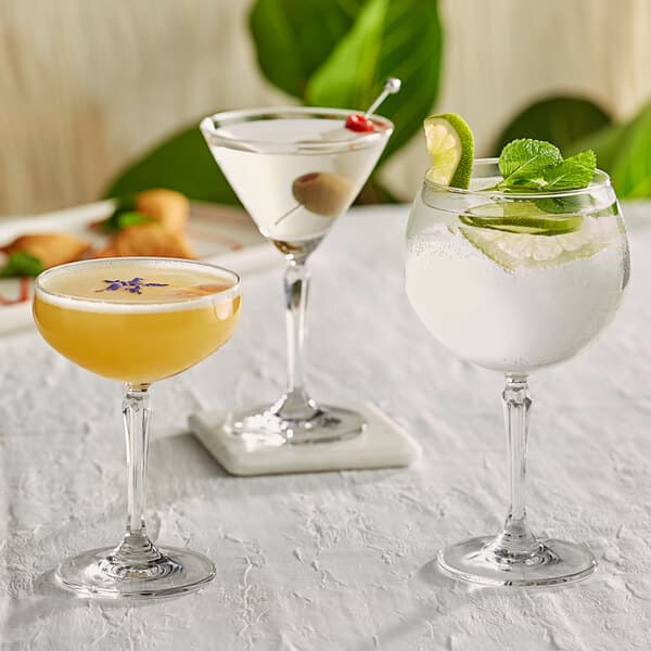 A close-up of an Acopa Empire martini glass filled with a yellow cocktail with a slice of lime on the rim.