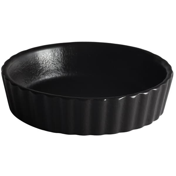 A black round dish with wavy edges on a white background.