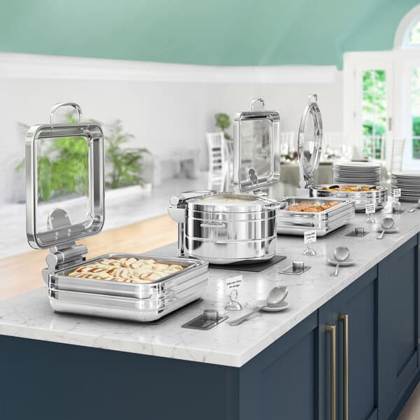 An Acopa Manchester stainless steel chafer with a glass top on a buffet line of food.