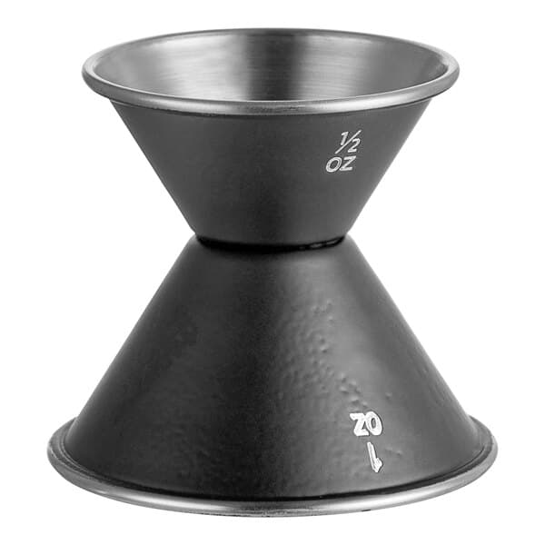 A black metal Acopa Classic Jigger with white text on a table in a cocktail bar.