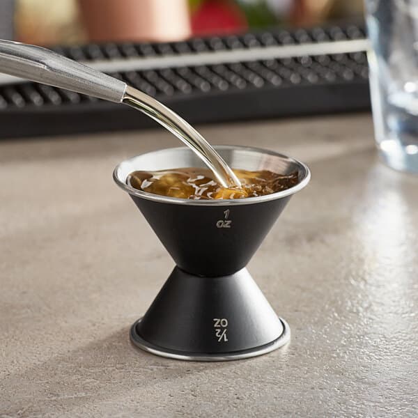 A metal funnel pouring liquid into a bowl.