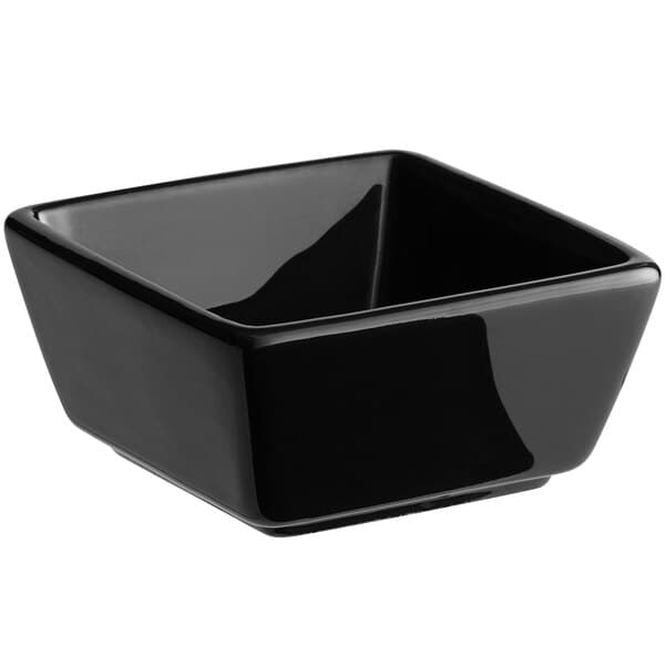 An Acopa glossy black square stoneware sauce cup on a counter.
