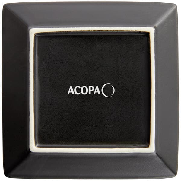 A black square Acopa stoneware plate with white text.