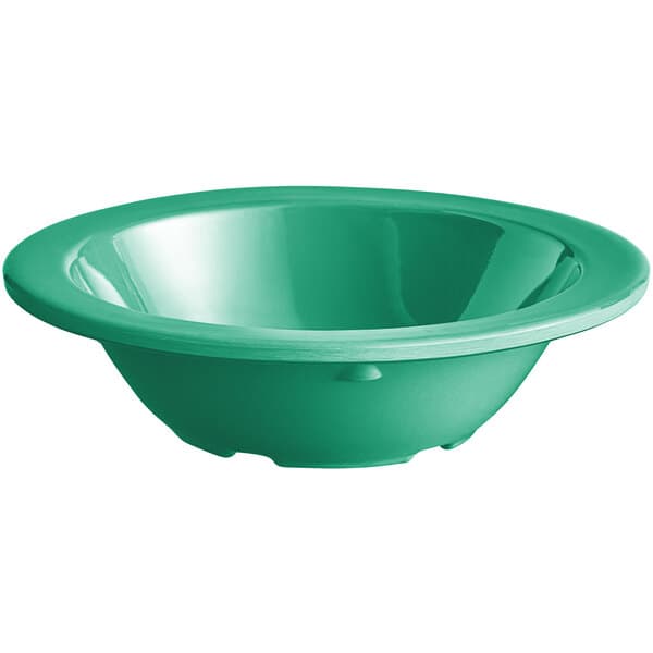 A close up of a green Acopa Foundations melamine fruit bowl.