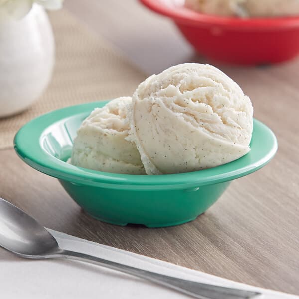 A green Acopa Foundations melamine bowl filled with fruit sits on a table.