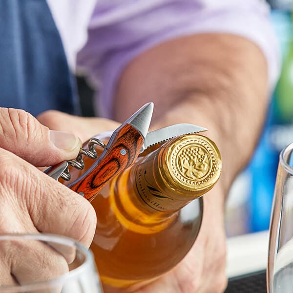 A person using an Acopa waiter's corkscrew to open a bottle of wine.