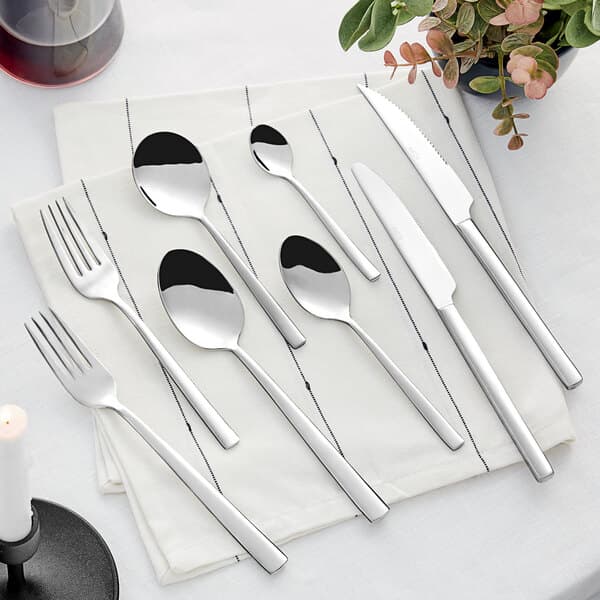 An Acopa stainless steel dinner spoon on a white surface.
