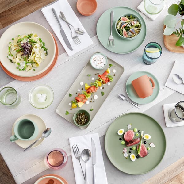 A table with Acopa mauve beverage glasses and plates of food and utensils.